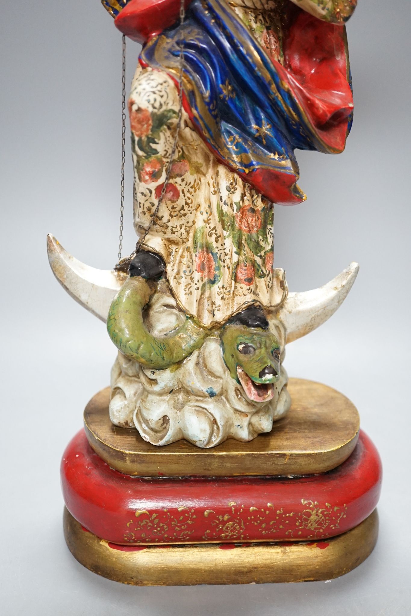 A painted South American angelic figure, standing on a dragon on a crescent moon 49cm